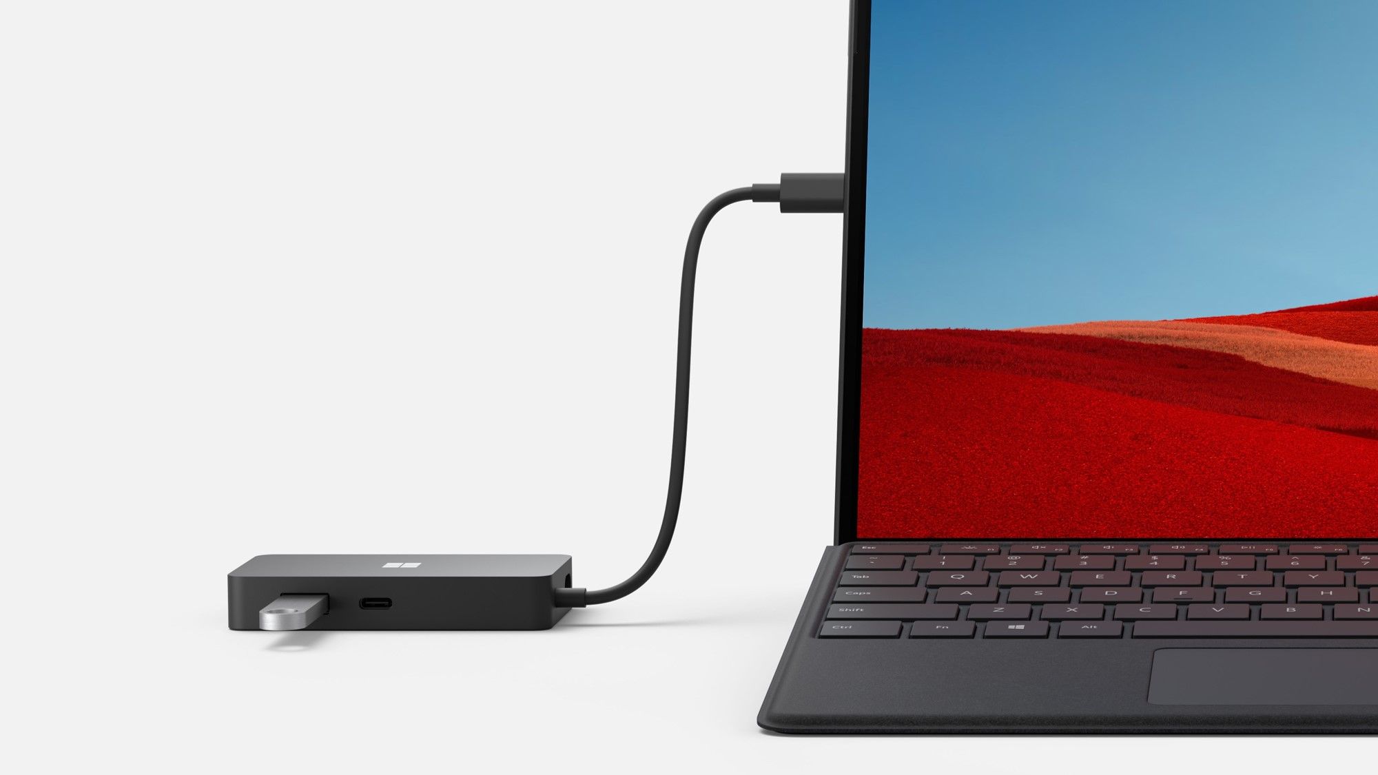 Das Surface USB-C Travel Hub ist mit einem USB-Stick und dem Surface Pro X verbunden