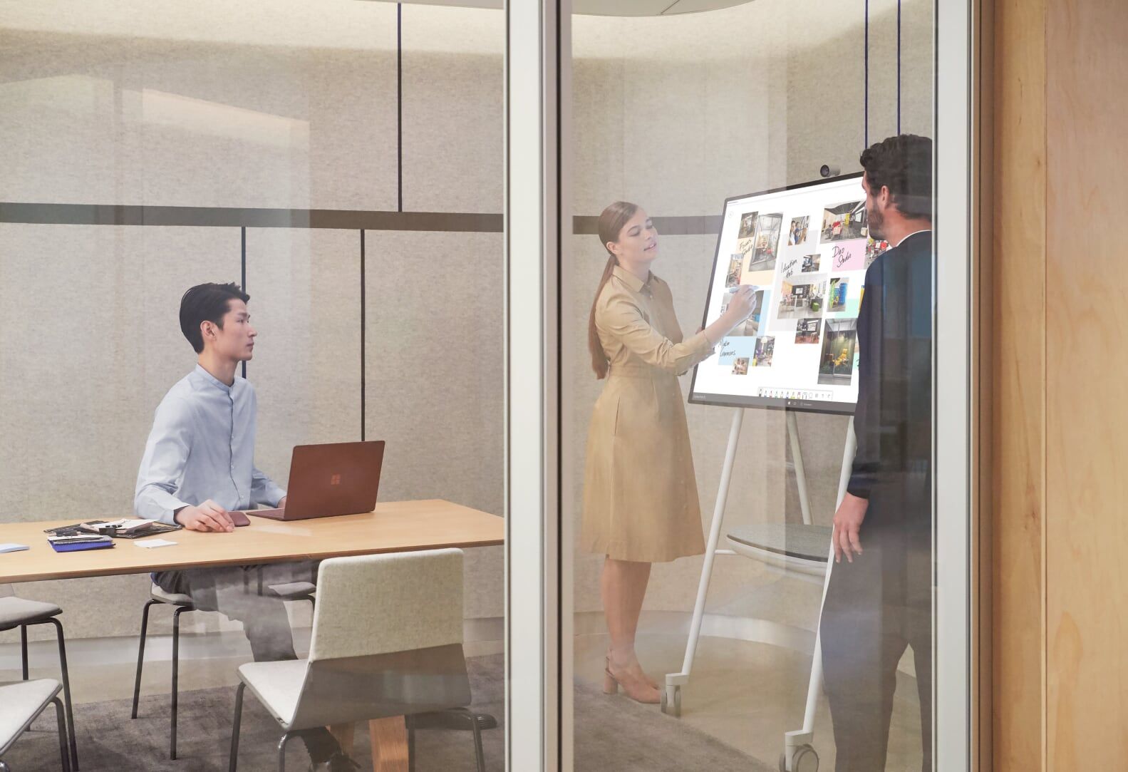 Tre personer arbejder sammen på et kontor, en kvinde skriver med Surface Hub 2 Pen på Surface Hub 2S 