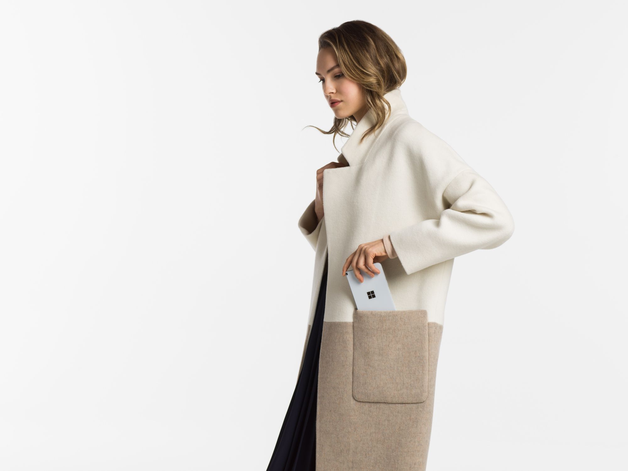 A woman puts the Surface Duo in the pocket of her coat