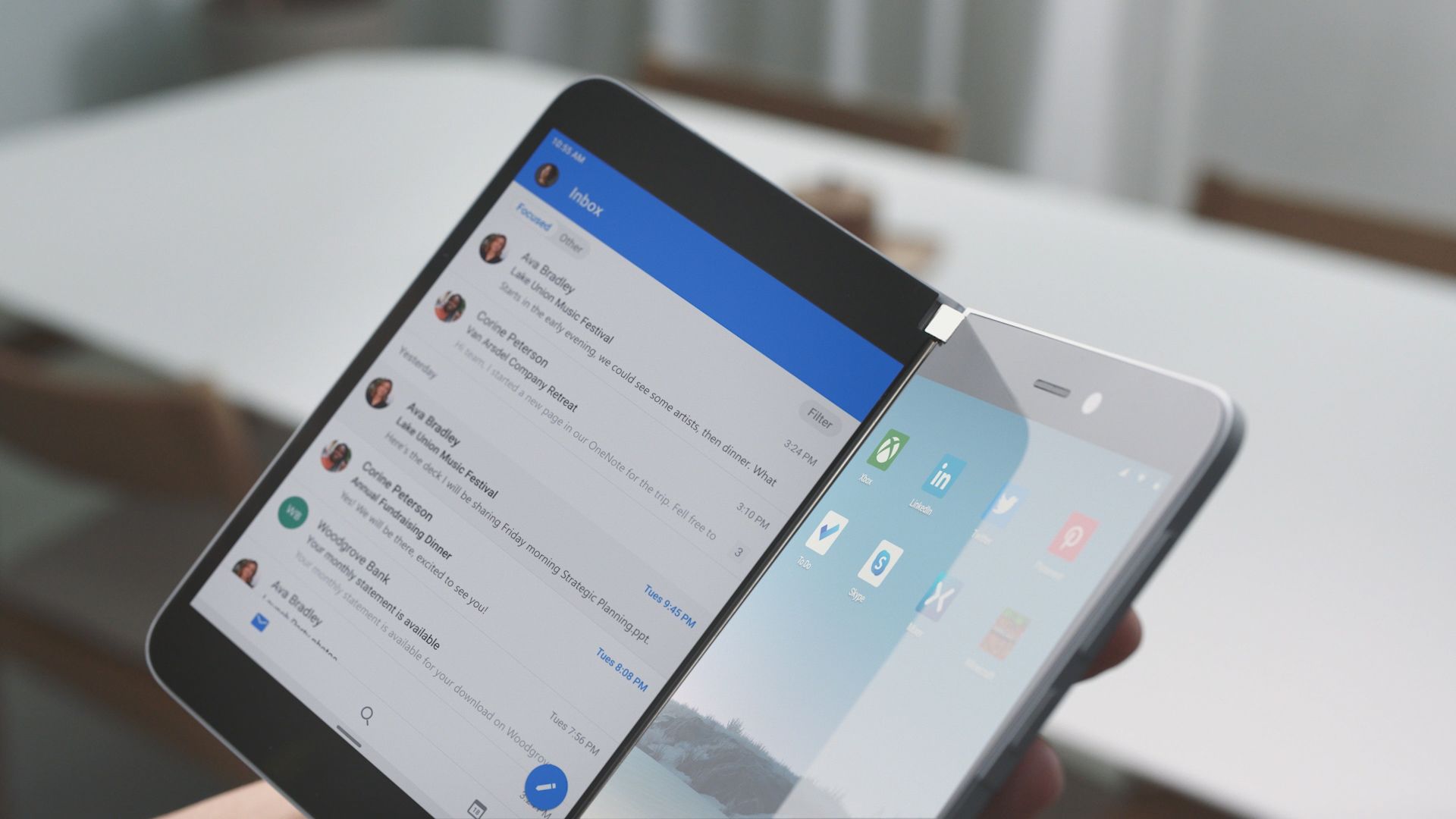 One hand holds the Surface Duo, the Outlook mailbox is opened on the left display