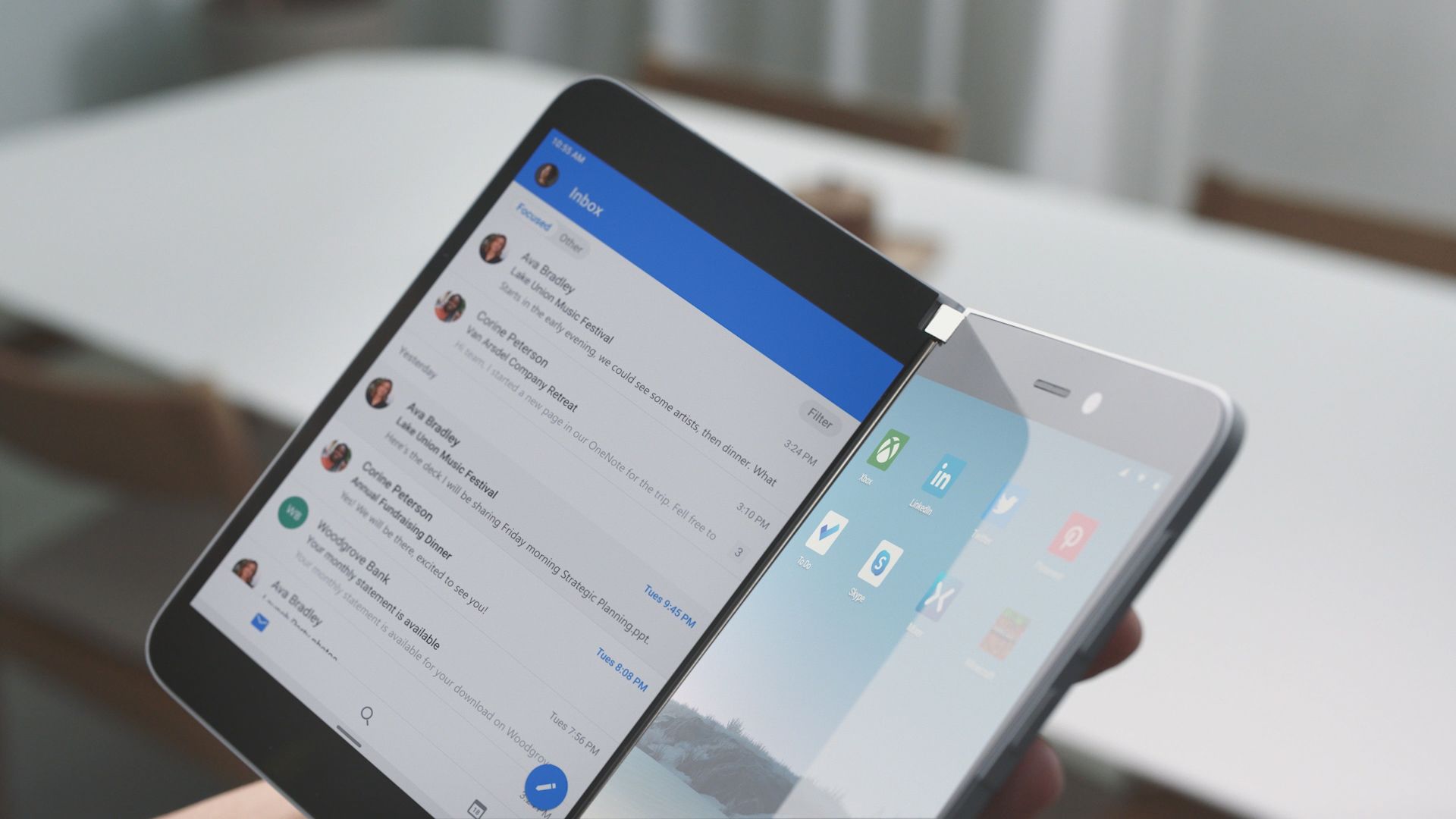 Eine Hand hält das Surface Duo auf dessen linken Bildschirm das Outlook-Postfach geoeffnet ist