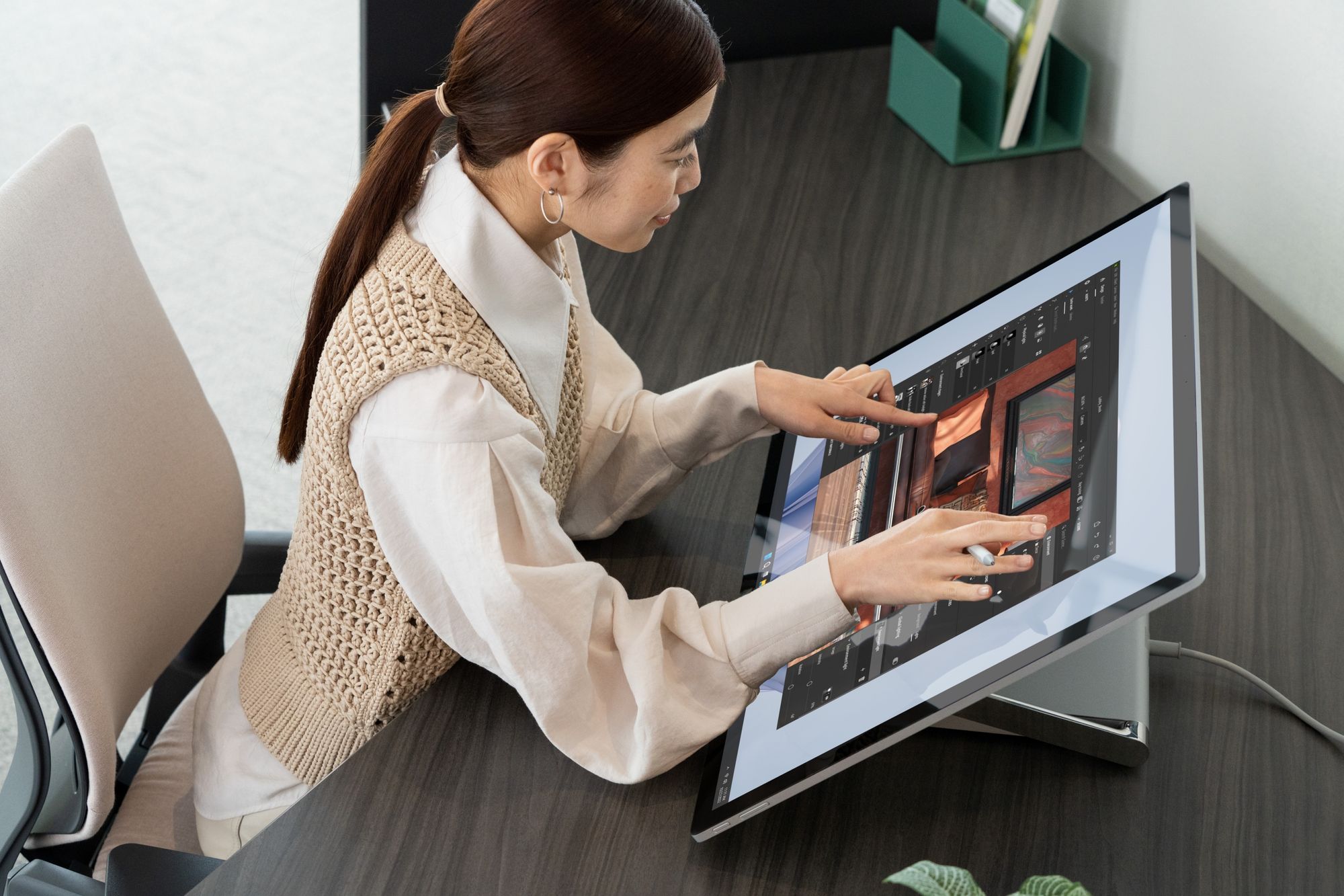 Woman sitting at a desk using the Surface Studio 2+ touch screen 