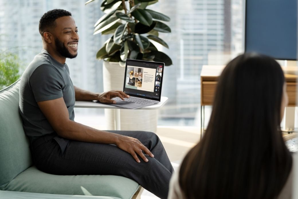 Man sitting on a couch in a conference room with his Surface Laptop 5 during a collaborative meeting