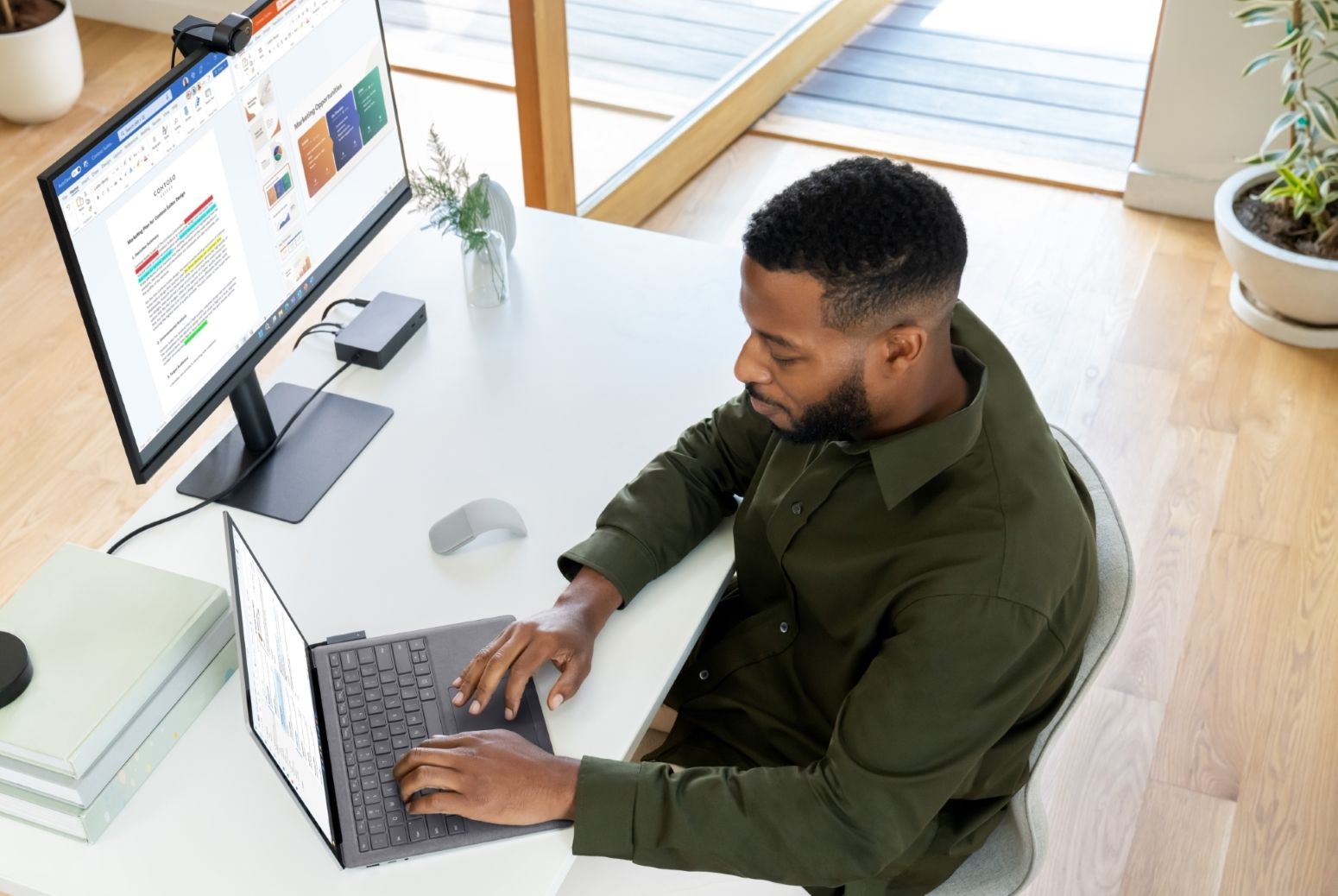 Man in home-office using the Surface Laptop 5 and Surface Dock 2 hooked up to a monitor and webcam