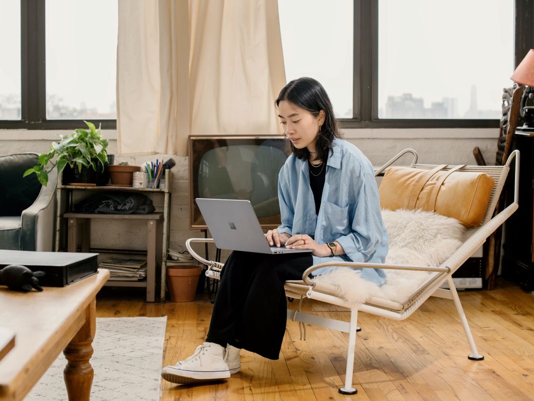 Woman sitting in a chair at home using the Surface Laptop 5 without a desk