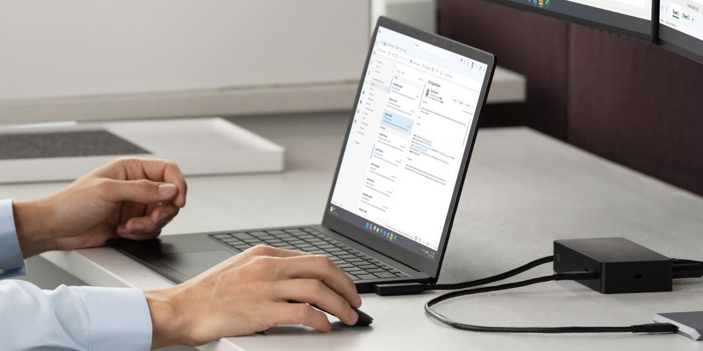 Close-up of man using the Surface Dock 2 to connect his Surface Laptop 5 to his monitor and charge a secondary device