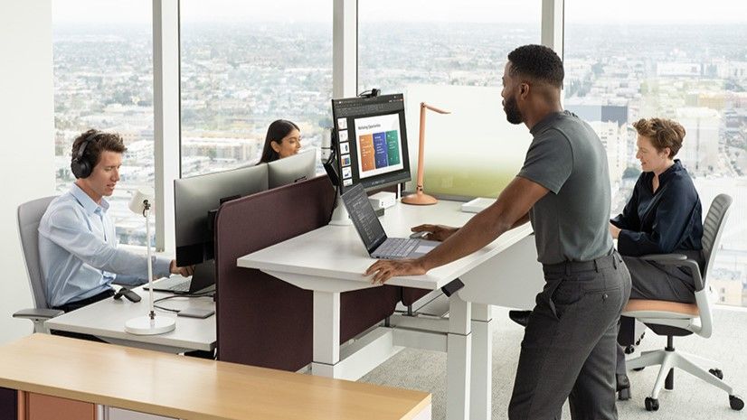 Four employees at their own desks using Surface Laptop 5 and Surface Arc Mouse with the Surface Dock 2 in order to connect to their desktop monitor